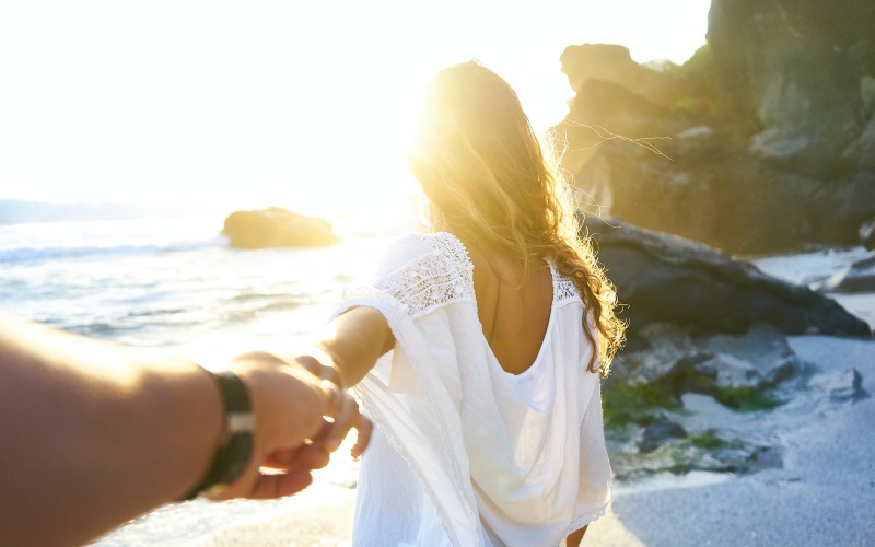 Choosing to become a mother: How I made my decision (photo of woman on beach grasping husband's hand)